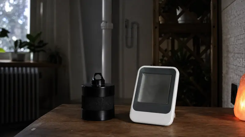 Short-term charcoal radon test canister next to a continuous digital monitor on a table